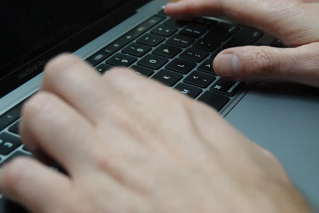 close-up of laptop keyboard and trackpad with hands typing