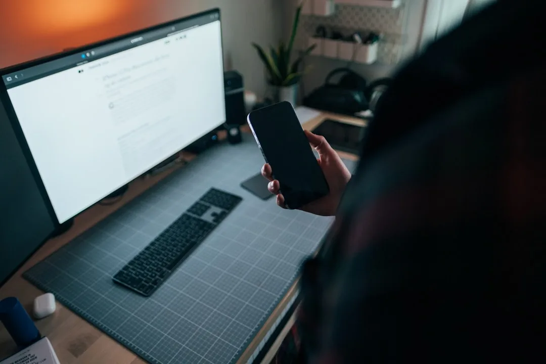 Designer reviewing a website wireframe and mobile layout on a monitor