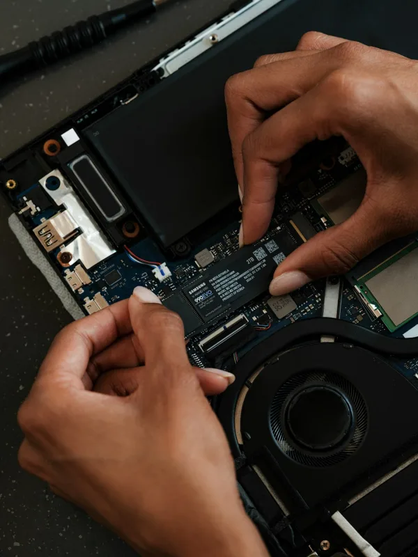 laptop motherboard with technician holding ribbon cable